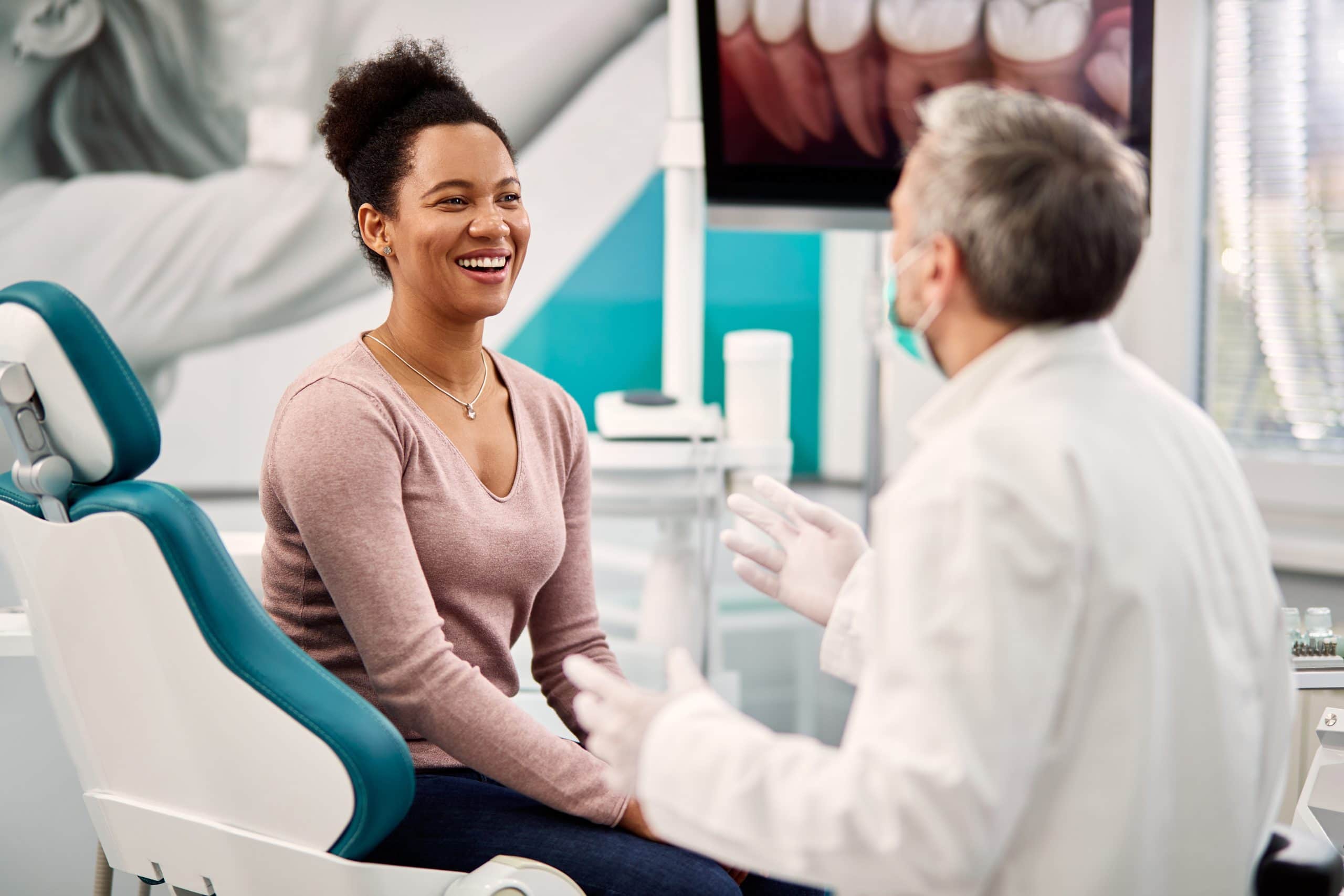 happy black woman talking to her dentist during appointment at dental clinic.
